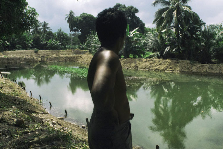A farmer named Azis stands near his small fish pond, polluted by coal dust and chemicals in Santan Ilir village in Indonesian Borneo. Photo by Ardiles Rante/Greenpeace.