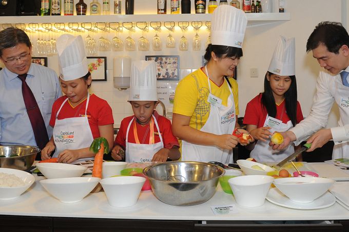 BT 20170920 AAt the launch of CapitaLand Hope Foundation's Kids' Food Fund 2013. CapitaLand CCO Mr Tan (far left) who is also executive director of the group's philanthropic arm looking on as the junior chefs do their thing. CapitaLand CEO Lim Ming Yan (right) and staff volunteer Joey Ng lending a helping hand to another `apprentice'. PHOTO: CAPITALANDLMXSIAS 3091208