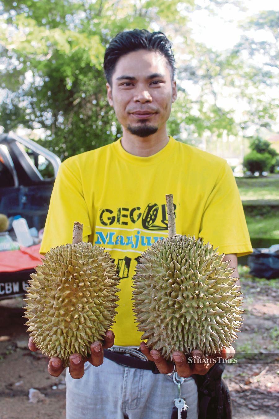 A durian seller showing off durian kampung. FILE PIC