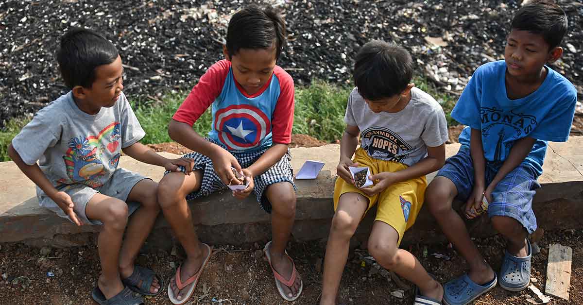 Children eat snacks next to the Jambe river filled with trash and household waste in Bekasi, West Java province on 2 November, 2019. (AFP Photo)