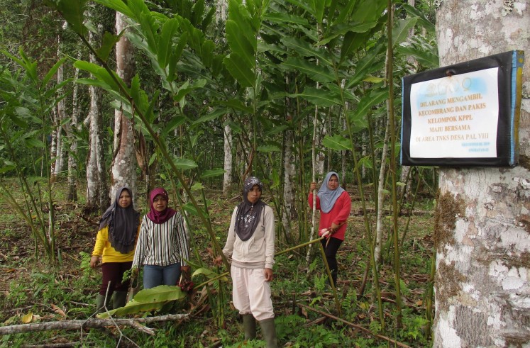 Members of farmers group Maju Bersama stand near a sign telling people to stay out of their cultivation area. (JP/Dedek Hendry)