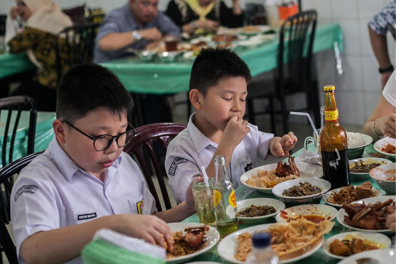 Two children in school uniform enjoy food at a Padang restaurant in Medan, North Sumatra. (JP/Andri Ginting)